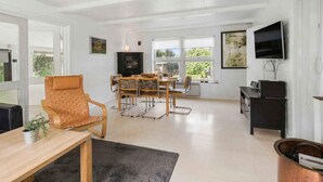 A spacious living room with a dining area, large windows, a flat-screen TV, and a fireplace. - 5 Star Holiday Home in Martofte (Martofte)