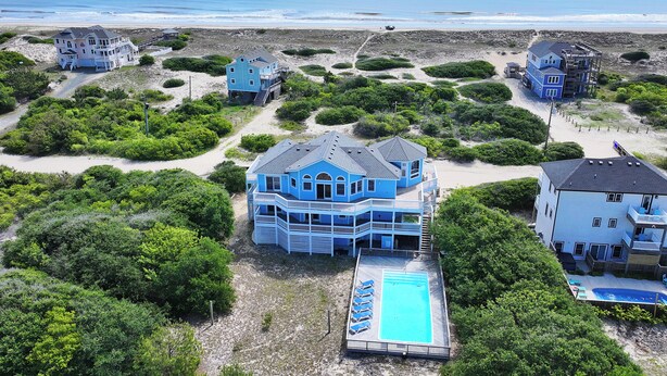 Una propiedad costera con varias construcciones, piscina y vista al mar.