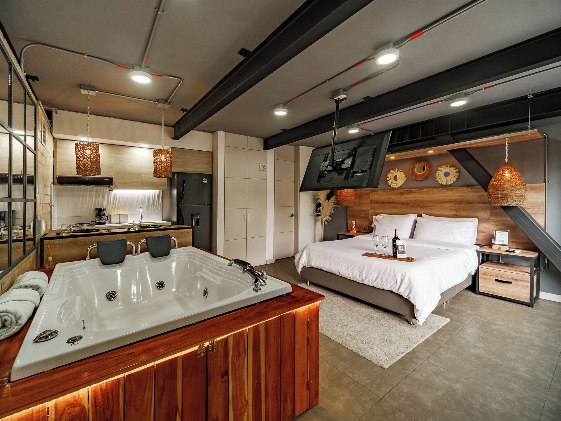 Een moderne hotelkamer met een groot bed, een aparte badkamer met whirlpool, een keukenhoek en een eethoek.