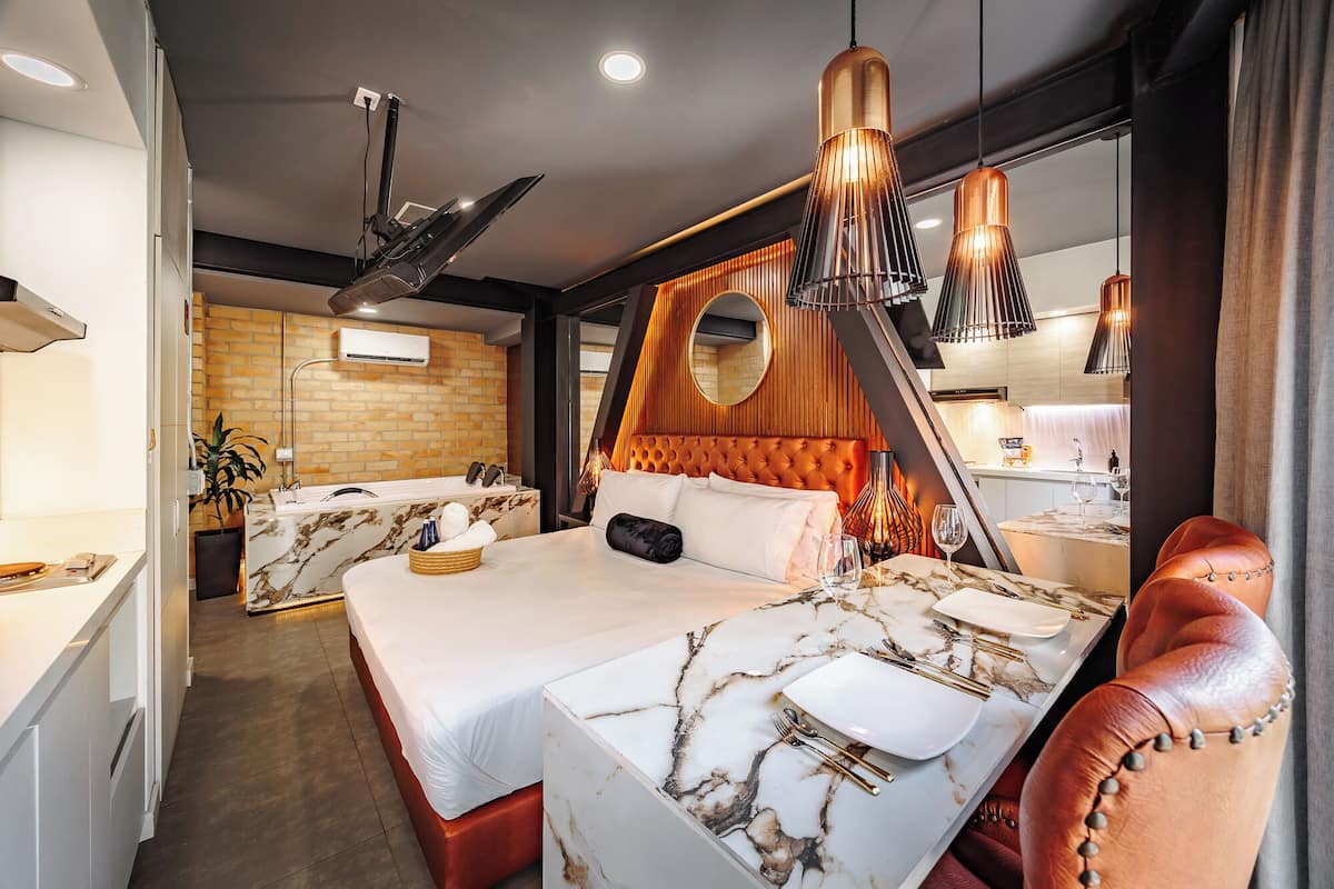 A hotel room with a bed, a desk, a chair, and a bathroom.