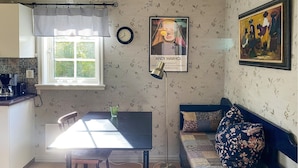 A cozy kitchen with a dining table, a sofa, and a wall clock.