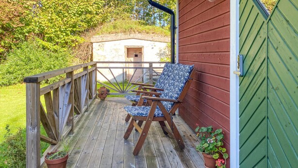 A wooden deck with two chairs and potted plants.