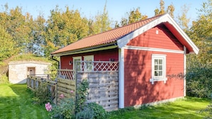 A red wooden house with a white window and a small porch.
