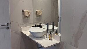 A modern bathroom with a large white sink, a mirror, and two towels hanging on the wall. - Charming 1-bedroom building in gorgeous Buenos Aires with fitness room, AC, wifi (Buenos Aires)