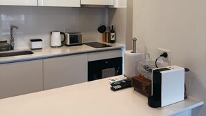 A modern kitchen with white cabinets, a built-in microwave, a kettle, and a coffee maker on the countertop. - Charming 1-bedroom building in gorgeous Buenos Aires with fitness room, AC, wifi (Buenos Aires)