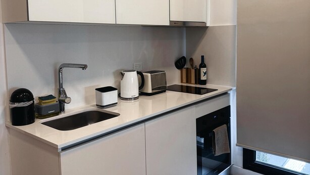 A modern kitchen with white cabinets, a stainless steel sink, a kettle, a toaster, and a wine bottle. - Charming 1-bedroom building in gorgeous Buenos Aires with fitness room, AC, wifi (Buenos Aires)