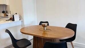 A modern dining area with a round wooden table, four black chairs, and a central decorative bowl. - Charming 1-bedroom building in gorgeous Buenos Aires with fitness room, AC, wifi (Buenos Aires)