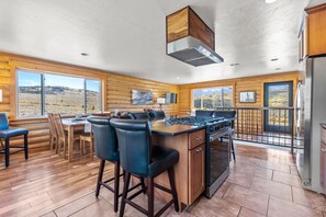 A modern kitchen with a central island, bar stools, and large windows offering scenic views.