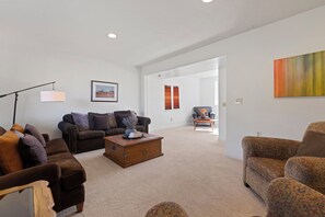 A living room with a sofa, armchairs, a coffee table, and a lamp. There is a painting on the wall and a window with curtains. - 5 Bedroom Log Cabin with Beautiful Mountain Views - Nearby Resorts (Silverthorne)