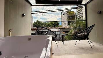 A modern outdoor space with a hot tub, a table, and chairs.