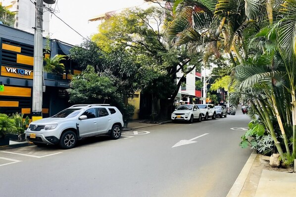 A street with parked cars and a building with a sign that reads "VIKTORY". - One Apartments Provenza (Medellín)