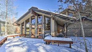 A modern house with large windows, a covered porch, and a snow-covered yard. - Serene Ski Retreat w/Elkhorn in SV amenity pass! (Sun Valley)
