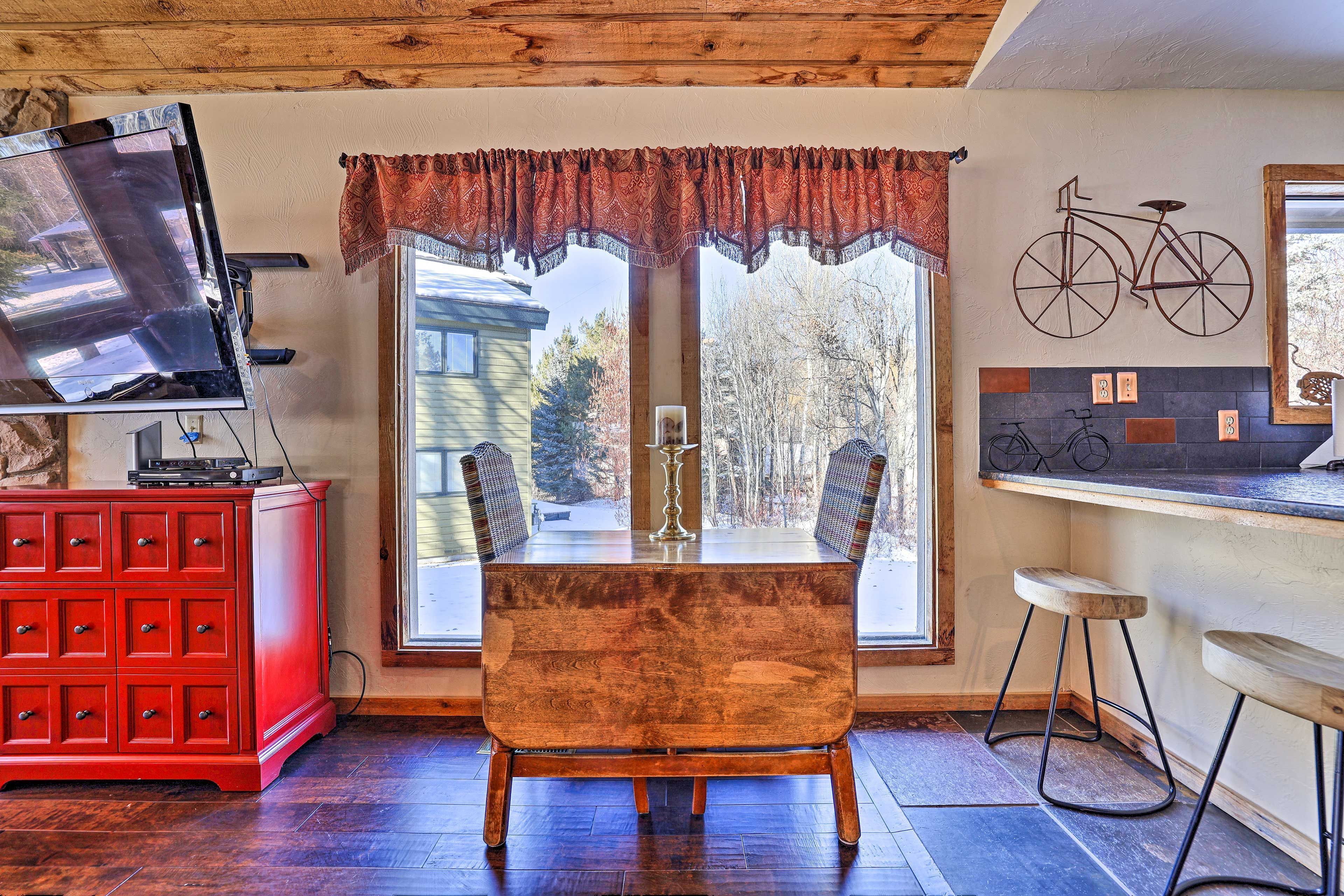 Uma área de refeições com uma mesa de madeira, um armário vermelho e uma bicicleta decorativa fixada na parede.