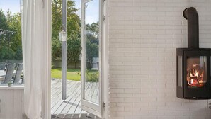 A room with a glass door leading to an outdoor deck, a fireplace, and a lantern. - 5 Star Holiday Home in Dronningmolle (Dronningmolle)
