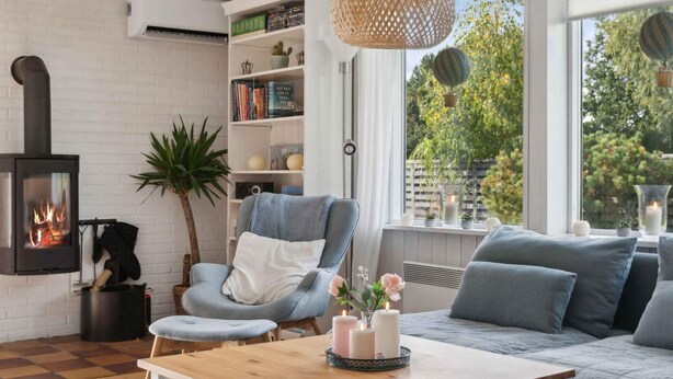 A cozy living room with a fireplace, a comfortable sofa, a wooden coffee table, and a bookshelf. - 5 Star Holiday Home in Dronningmolle (Dronningmolle)