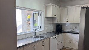 Una cocina moderna con armarios blancos, encimera negra y refrigerador de acero inoxidable.