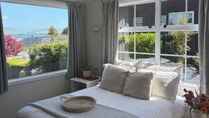 Un dormitorio con una cama grande, una mesita de noche con una planta y una ventana con cortinas.