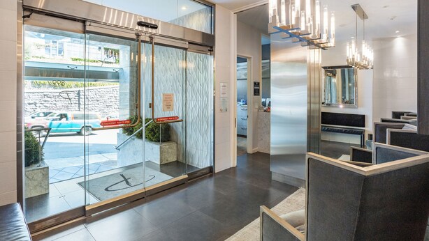 A modern hotel lobby with a glass entrance, a reception desk, and a seating area.