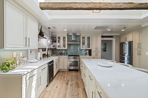 A spacious kitchen with white cabinetry, a large island, and a wooden floor.