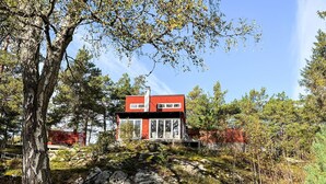 A modern house with a red exterior, large windows, and a stone foundation. - 4 Star Holiday Home in Stavsnas (Stavsnäs)