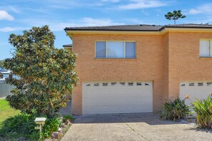 A two-story house with a brick facade, a garage, and a well-maintained garden with various plants.