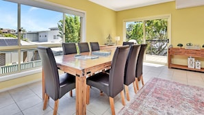 Un comedor con una mesa de madera, sillas negras y vista al exterior.