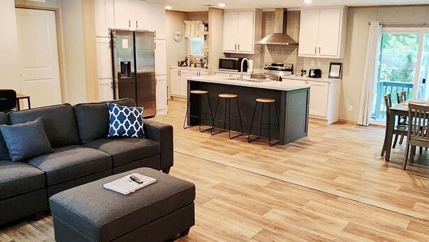 A modern kitchen with a central island, bar stools, and a dining area with a table and chairs. - 3-bedroom house in delightful Hilton Head Island, SC (Hilton Head Island)