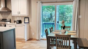 A modern kitchen with white cabinets, a built-in oven, and a dining area with a wooden table and chairs. - 3-bedroom house in delightful Hilton Head Island, SC (Hilton Head Island)