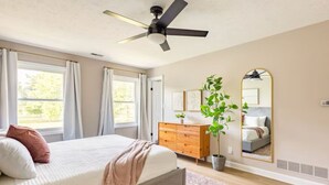 A bedroom with a bed, a dresser, a mirror, and a ceiling fan.
