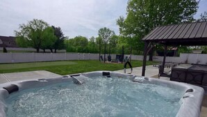 A hot tub with a wooden deck and a pergola in the background.