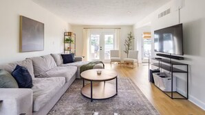 A modern living room with a sectional sofa, a coffee table, a TV, and a bookshelf.