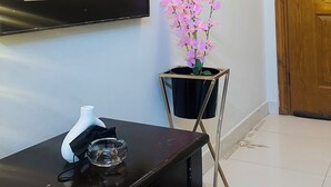 Ein Zimmer mit einem großen Spiegel, einem Wanddekor, einer Holztür und einem kleinen Tisch mit einer Vase und einem Glas.