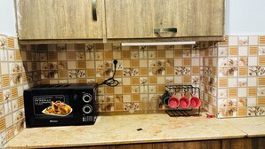Eine Küche mit einem schwarzen Toaster auf der Arbeitsplatte, einer gefliesten Spritzschutzwand mit floralem Muster und einem Topfhalter mit roten Töpfen.