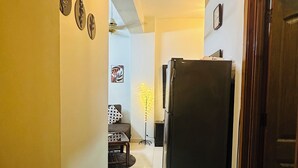 Ein Flur mit Kühlschrank, Blumentopf und Tür rechts.