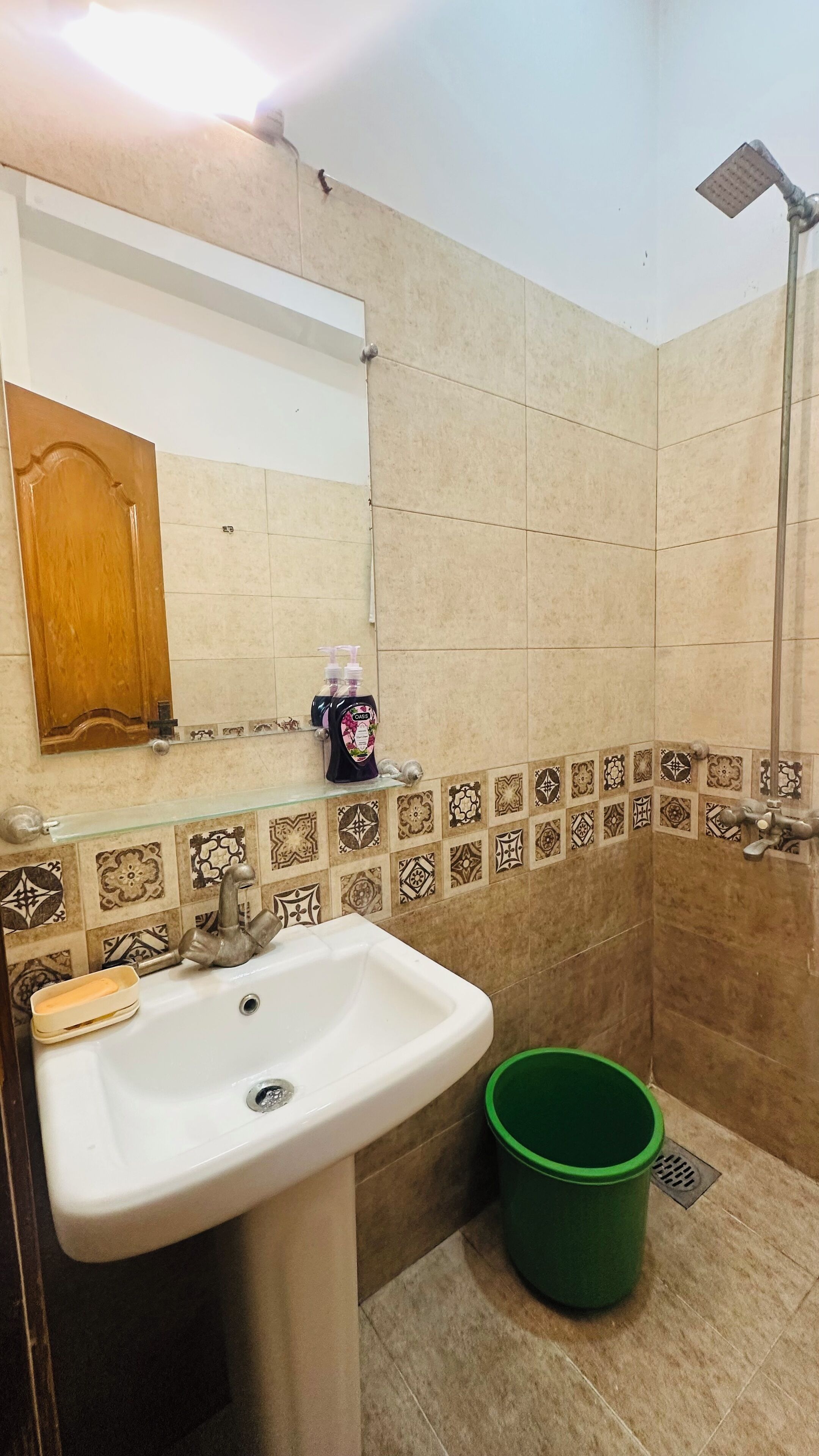 A bathroom with a sink, mirror, shower, and decorative tiles.