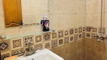 A bathroom with a sink, mirror, shower, and decorative tiles.