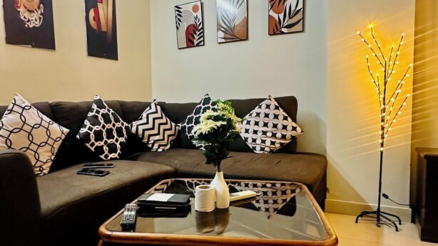 Ein Wohnzimmer mit einem dunkelbraunen Sofa, einem Glastisch und drei gerahmten Kunstwerken an der Wand.