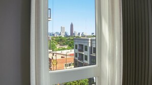 Une vue sur la ville, avec ses bâtiments, à travers une fenêtre, sous un ciel dégagé.