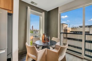 A balcony with a table and chairs, a view of the cityscape, and a modern kitchen area. - Cozy Stay ATL -2BD/2BTH FreeParking & 5* Amenities (Atlanta)
