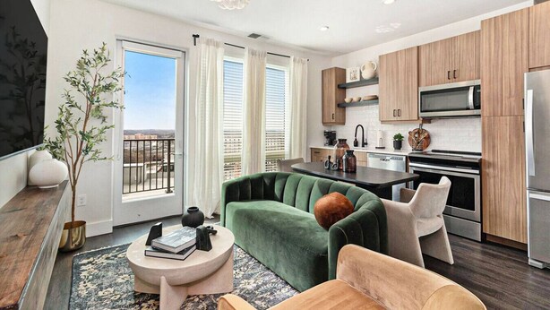 Un apartamento moderno con sofá verde, una mesa de comedor y una zona de cocina.