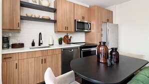 Una cocina moderna con armarios de madera, un refrigerador de acero inoxidable, un microondas y una cafetera.