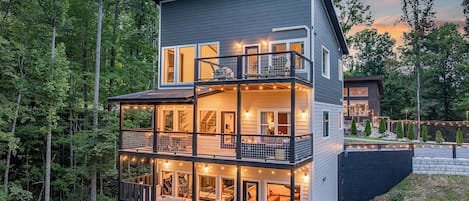 A multi-level house with a balcony, a hot tub, and a deck area.