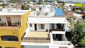 Un edificio residencial de varios pisos con techo plano, garaje y balcón con macetas.