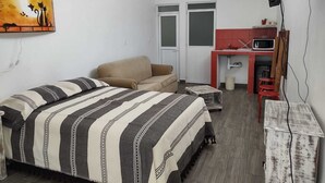 Un dormitorio con cama, sofá, escritorio y televisor.