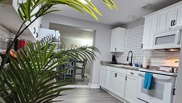 A modern kitchen with white cabinets, a double oven, and a tiled backsplash. - Seaside Serenity-Tranquil Beachside 2-bedroom home in beautiful Ormond-By-Sea (Ormond Beach)