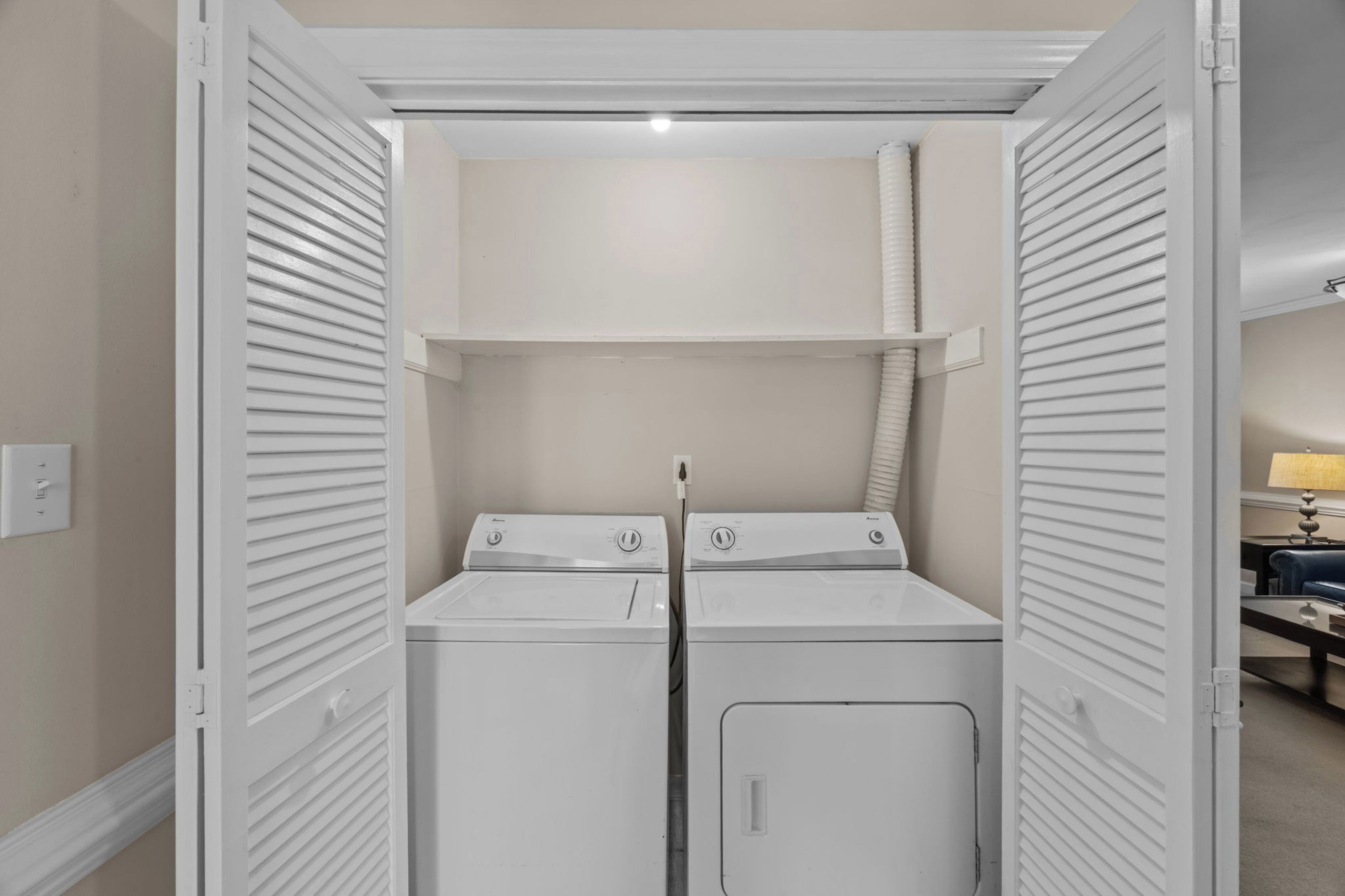A laundry room with two stacked washers and dryers, a vent, and a power outlet on the wall.