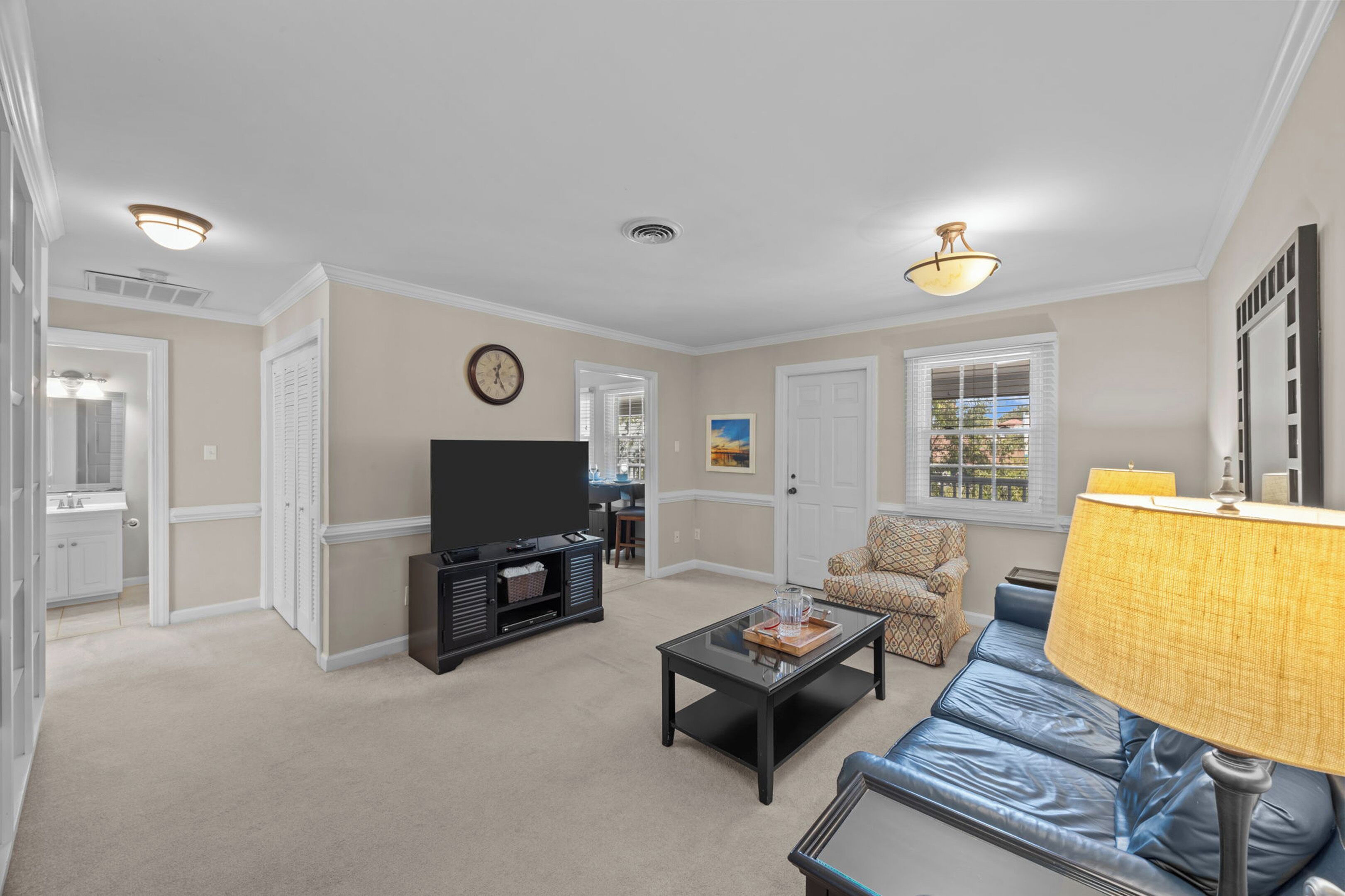 A living room with a flat-screen TV, a coffee table, a sofa, and a lamp.