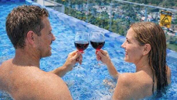A couple toasting with wine glasses in a rooftop infinity pool overlooking a cityscape. - LUJOSO APTO NORTE DE ARMENIA (Armenia)