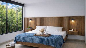 A bedroom with a wooden headboard, a large window with a view of trees, a bed with white linens, and bedside tables with lamps. - LUJOSO APTO NORTE DE ARMENIA (Armenia)