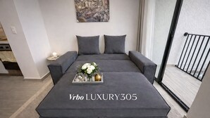 A modern, grey upholstered sofa bed with a tray of white flowers and a gold teapot on the center. - LUJOSO APTO NORTE DE ARMENIA (Armenia)